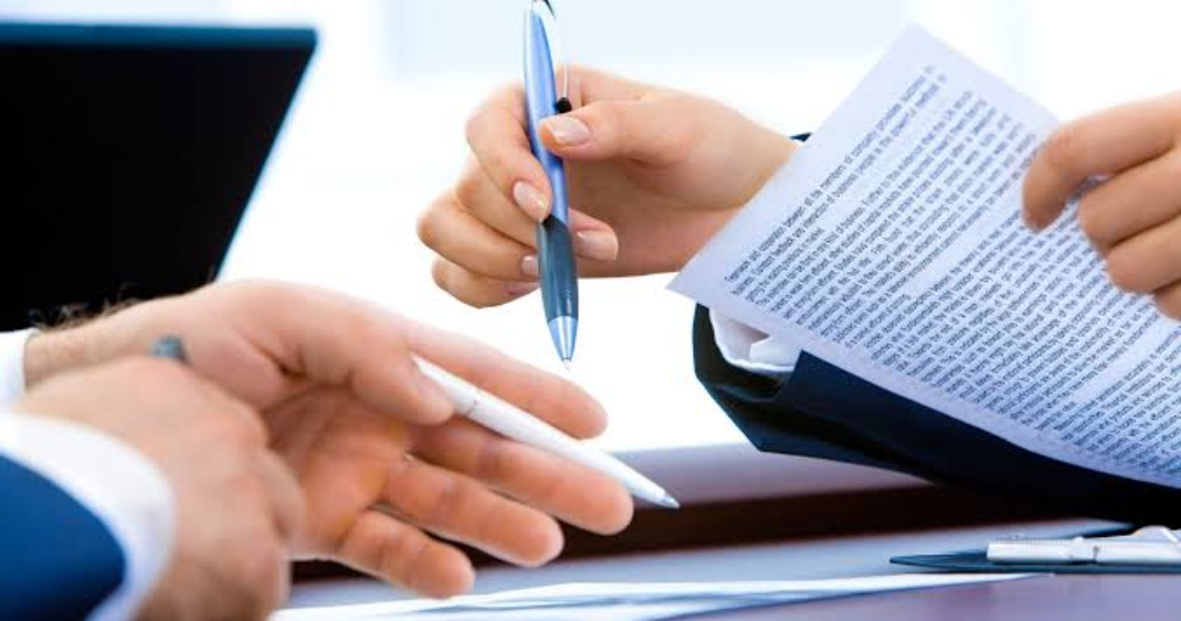Dos personas firmando un contrato.