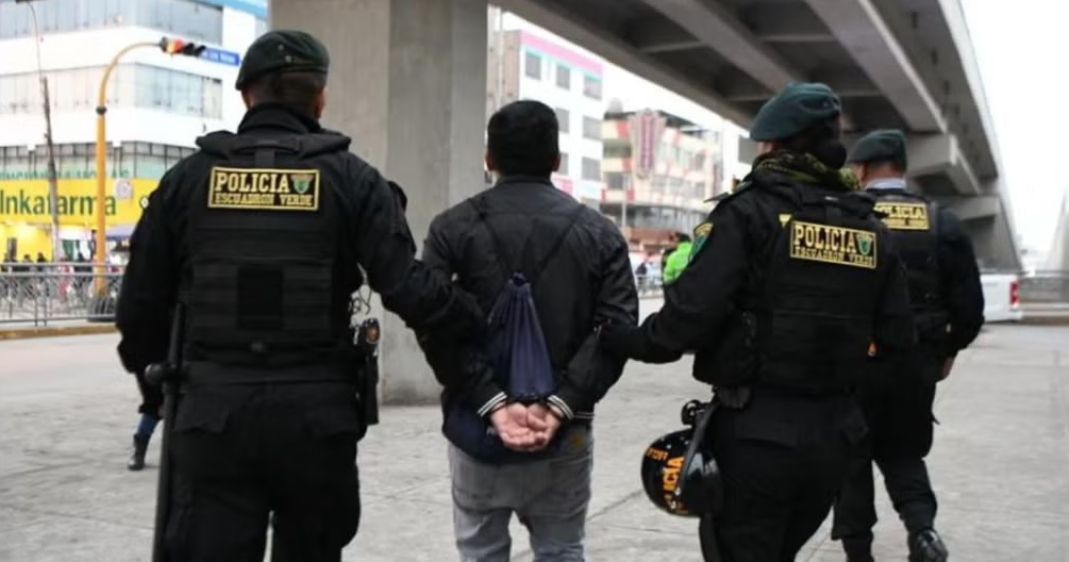 Operativo de seguridad ciudadana: efectivos policiales trasladan a un sujeto intervenido en una calle urbana bajo un puente.
